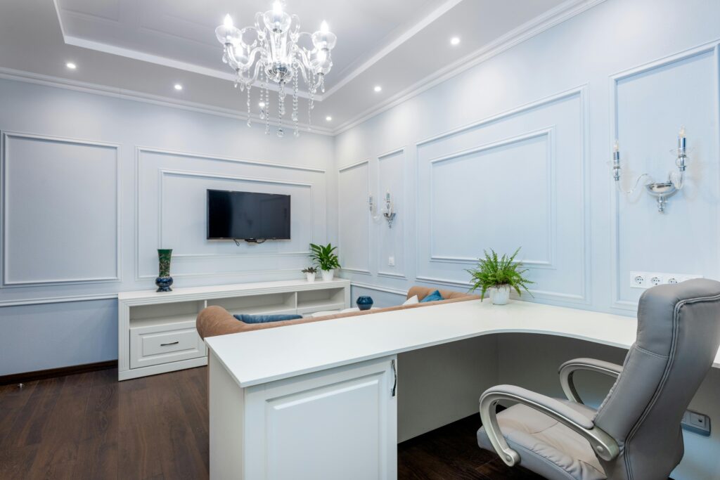 pexels photo 8135119 8135119 Luxurious office interior with minimalist design, featuring white furniture, chandelier, and flat-screen TV.